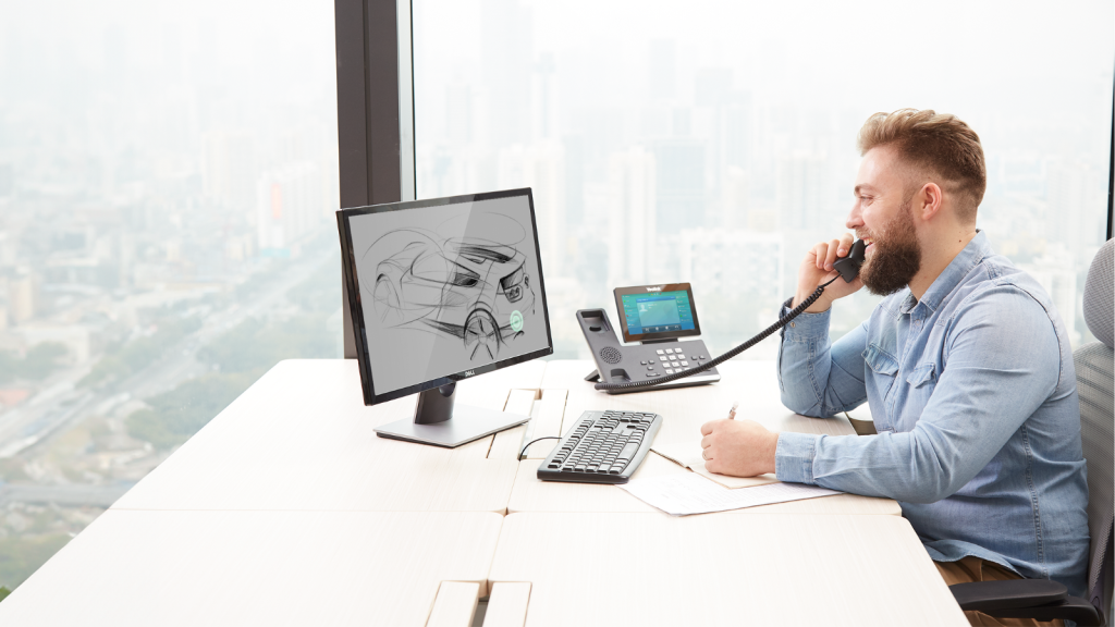 A businessman sits at his desk using business phone systems to continue with his project across teams