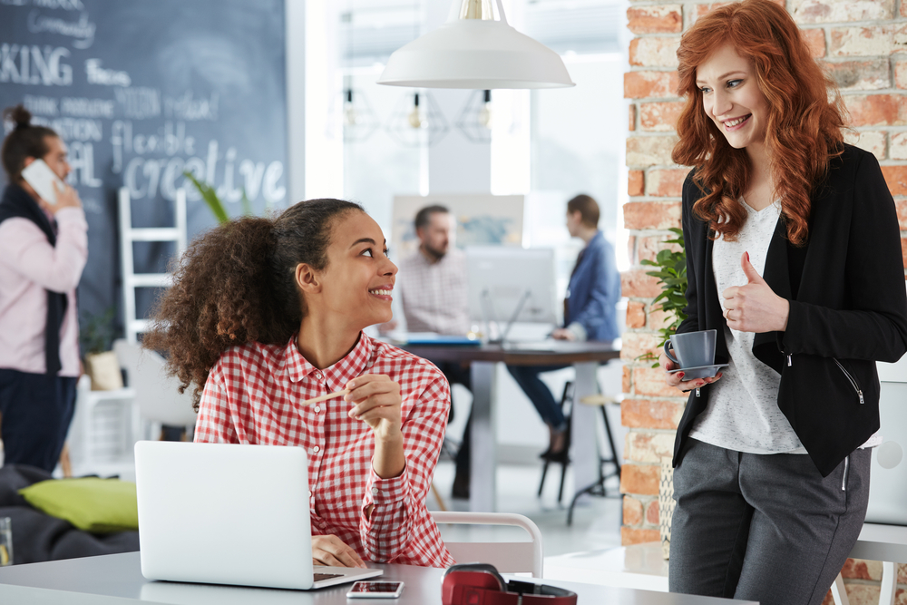Young women working in a creative agency, talking and smiling