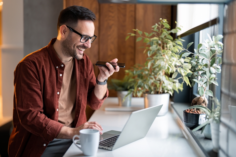 Remote worker using a mobile phone with VoIP phone service while working remotely on a laptop